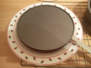 The side of the cake pan have been removed, leaving the base on the cake